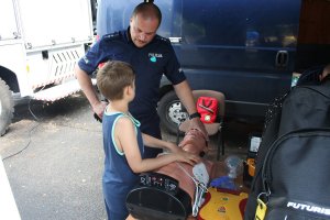 policjant tłumaczy dziecku zasady udzielania pierwszej pomocy