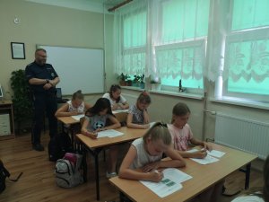 policjant obserwuje piszących test uczniów