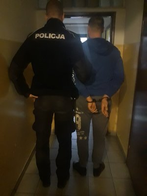 policjant prowadzi zatrzymanego mężczyzne