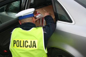 policjant wyjmuje z samochodu papierosy