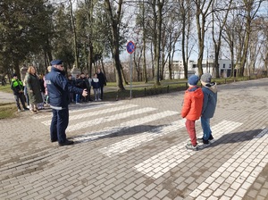policjant stoi przy przejsciu dla pieszych gdzie przechodza dzieci