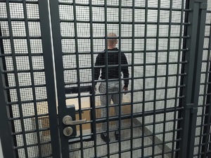 zatrzymany mężczyzna stoi w pomieszczeniu zatrzymanych za kratami