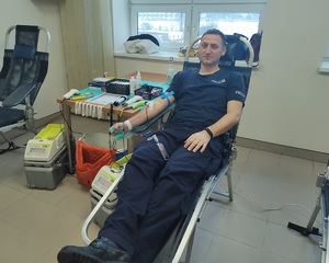 policjant siedzący na stanowisku do oddawania krwi