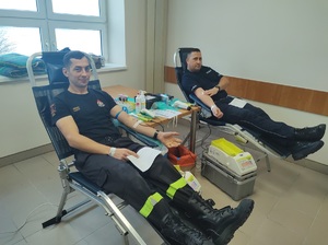 policjant i strażak siedza na stanowisku do oddawania krwi