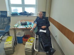 policjant siedzacy na stanowisku do oddawania krwi