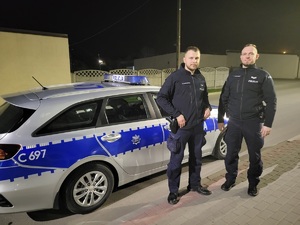 dwóch policjantów stojących przed radiowozem